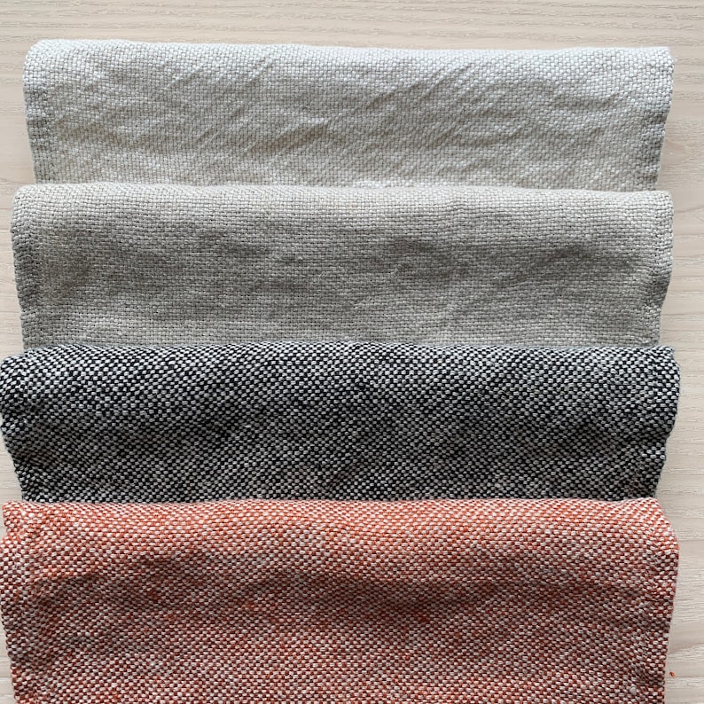 May include: Four fabric swatches in different colors and textures. The top swatch is a light beige linen, the second is a darker beige linen, the third is a black and white tweed, and the bottom is a rust-colored tweed.