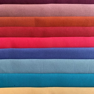 May include: A stack of ten fabric swatches in various colors, including purple, burgundy, pink, orange, red, pink, blue, light blue, teal, and beige.
