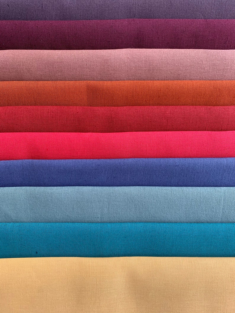 May include: A stack of ten fabric swatches in various colors, including purple, burgundy, pink, orange, red, pink, blue, light blue, teal, and beige.