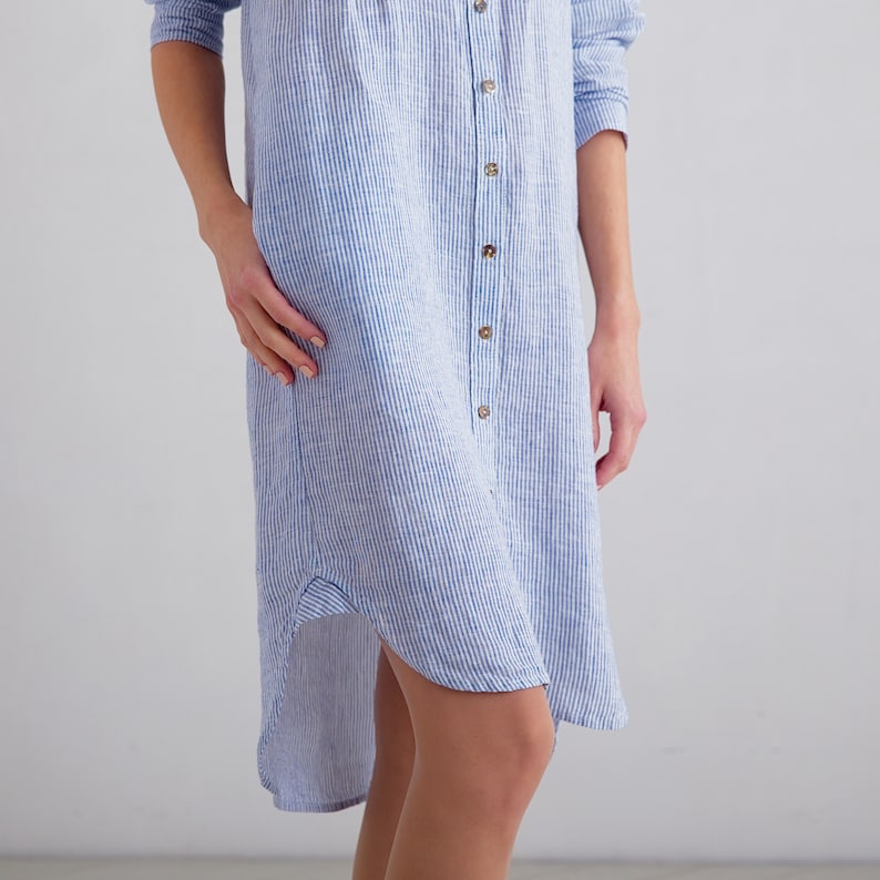 Puede incluir: Un vestido camisa de lino a rayas azules y blancas con cierre de botones y un dobladillo alto-bajo.