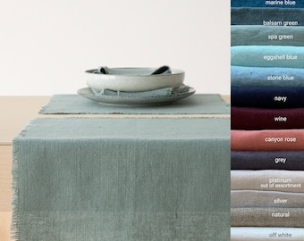 May include: A light blue linen table runner with frayed edges. The runner is on a wooden table with two bowls and napkins.