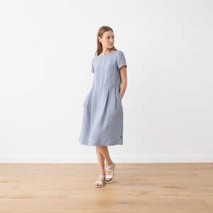 May include: A light blue linen dress with short sleeves and a slightly flared skirt. The dress has a simple, classic design and is perfect for warm weather.