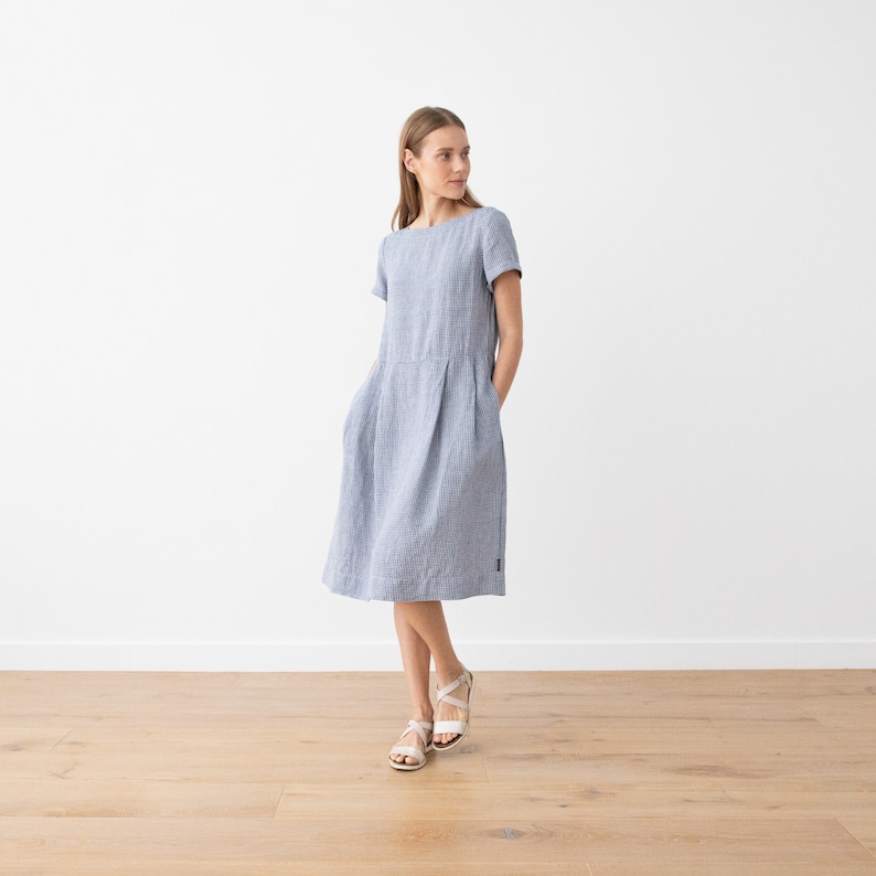 May include: A light blue linen dress with short sleeves and a slightly flared skirt. The dress has a simple, classic design and is perfect for warm weather.