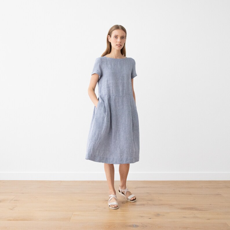 May include: A blue and white striped linen dress with short sleeves and pockets. The dress has a relaxed fit and falls to the knee.