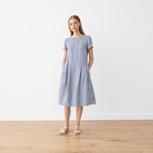 May include: A blue and white striped linen dress with short sleeves and pockets. The dress has a relaxed fit and falls to the knee.