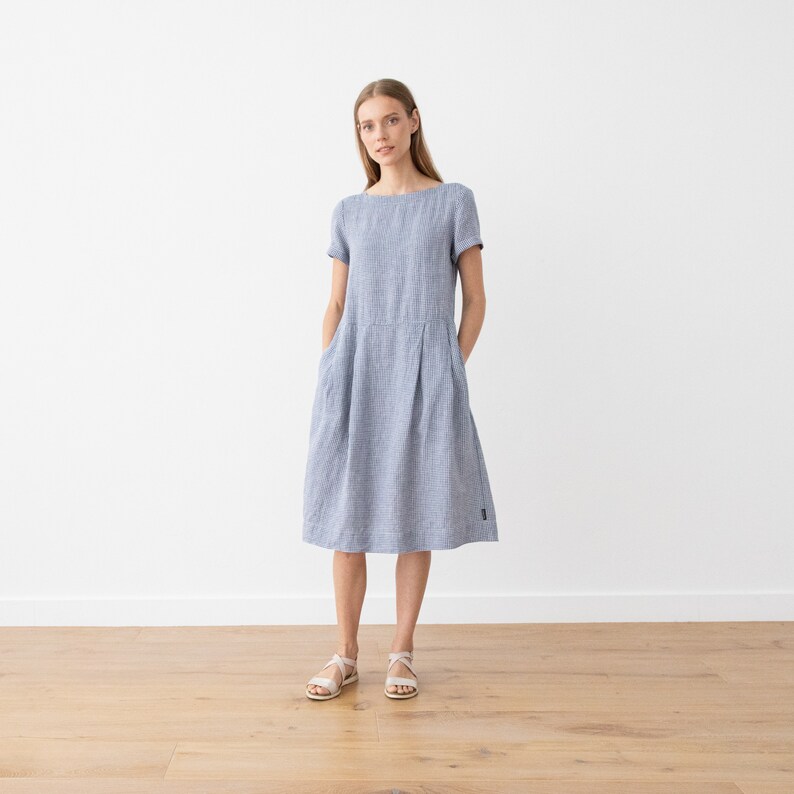 May include: A blue and white striped linen dress with short sleeves and pockets. The dress has a relaxed fit and falls to the knee.