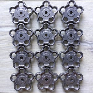 Puede incluir: Doce pomos de metal de color plateado con un diseño de estrella y un agujero en el centro. Cada pomo tiene los números "0-3" impresos en él.