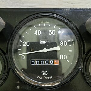 May include: A black dashboard with a speedometer that reads 000004 km/h. The speedometer has a white needle and a black face with white markings. The text "СП 1168" and "ГОСТ 1598-76" are visible on the face of the speedometer.