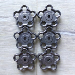 Może przedstawiać: Sześć srebrnych metalowych gałek z wzorem gwiazdy i małym otworem w środku. Każda gałka ma liczby "0" i "3" po obu stronach otworu.