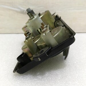 May include: Close-up of a black metal gauge cluster with four round gauges. The gauges are silver and have black needles. The cluster is mounted on a white surface.
