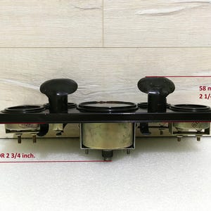 May include: Black metal gauge panel with four round gauges, two with black bezels and two with silver bezels. The panel measures 2 3/4 inches by 2 1/4 inches.