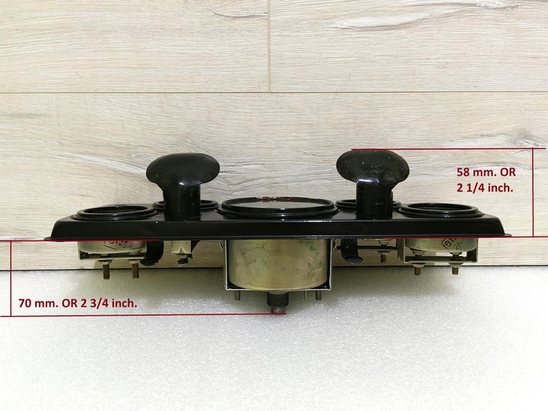 May include: Black metal gauge panel with four round gauges, two with black bezels and two with silver bezels. The panel measures 2 3/4 inches by 2 1/4 inches.