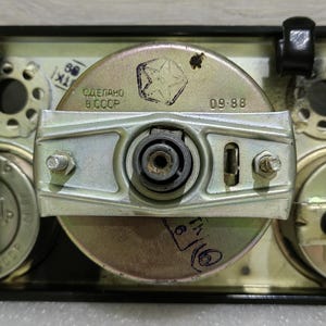 May include: Close-up of a silver-colored gauge with a black background. The gauge has a star-shaped logo and the text "СДЕЛАНО В СССР" and "09-88".