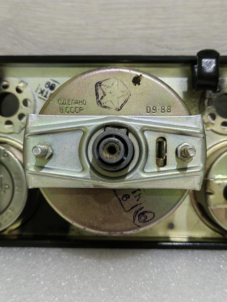 May include: Close-up of a silver-colored gauge with a black background. The gauge has a star-shaped logo and the text "СДЕЛАНО В СССР" and "09-88".
