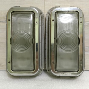 Könnte beinhalten: Zwei rechteckige Vintage-Automatikleuchten aus verchromtem Metall mit klaren Glasscheiben. Die Leuchten haben eine abgerundete Kante und einen erhöhten Rand um das Glas.