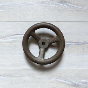 Könnte beinhalten: Ein großes, rundes, braunes Metallrad mit drei Speichen und einem quadratischen Loch in der Mitte. Das Rad hat die Nummer "150" aufgedruckt.