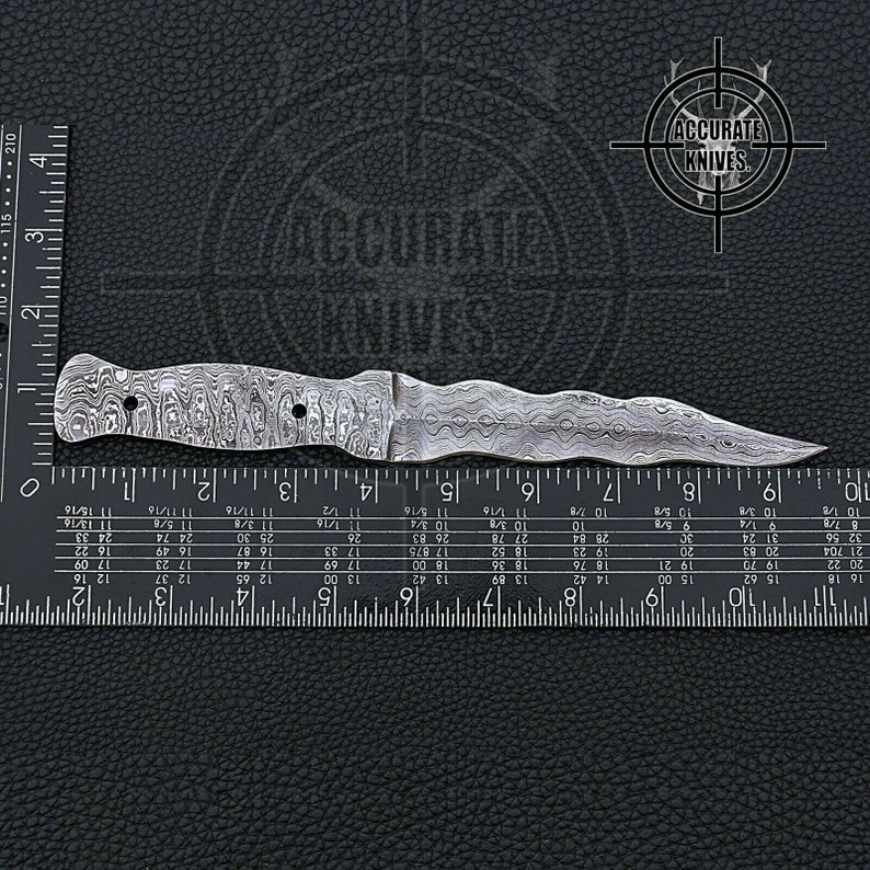 May include: A Damascus steel dagger with a wavy blade and handle. The knife is approximately 9 inches long, with a detailed pattern on the metal. The Accurate Knives logo is visible in the background.