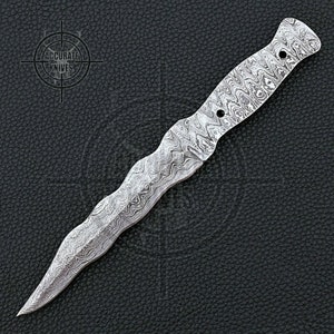 May include: A Damascus steel dagger with a wavy pattern. The blade is pointed and the handle has a textured grip with two holes. The logo "ACCURATE KNIVES" is in the upper left corner.