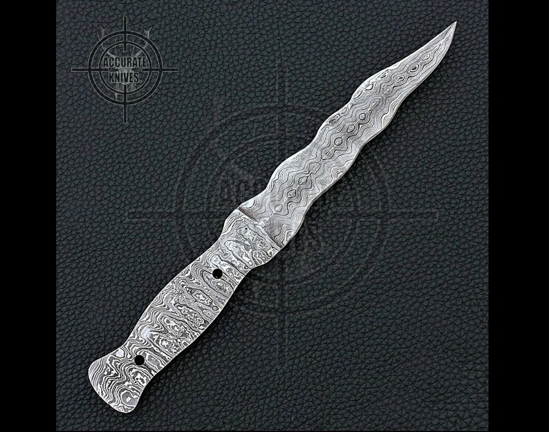 May include: A Damascus steel dagger with a wavy handle and a pointed blade. The knife has a unique pattern and is set against a dark textured background. The text "ACCURATE KNIVES" is visible in the upper left corner.