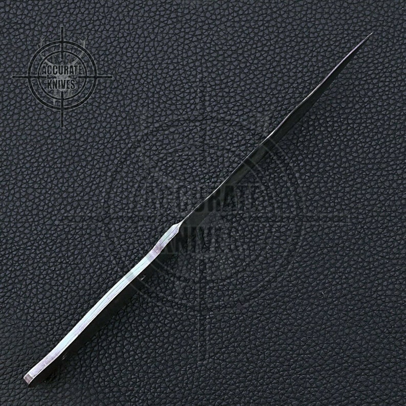 May include: A black knife with a long, slender blade. The knife is set against a dark, textured background. The text "ACCURATE KNIVES" is visible in the upper left corner.