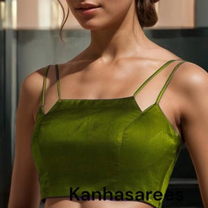 May include: A green satin crop top with thin straps. The top has a square neckline and a fitted silhouette. The text "Kanhasarees" is visible on the front of the top.