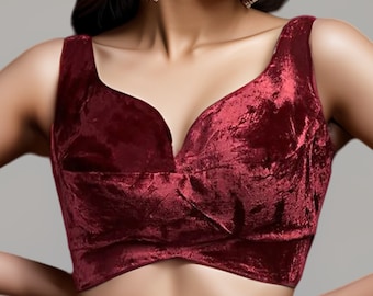 May include: A maroon velvet crop top with a deep V-neckline and a criss-cross design in the front.