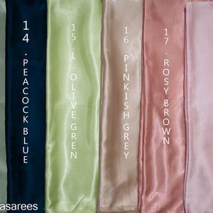 Puede incluir: Muestra de seis muestras de tela en varios colores: verde salvia, azul pavo real, verde oliva claro, gris rosado, marr&oacute;n rosado y rosa beb&eacute;. Cada muestra est&aacute; etiquetada con un n&uacute;mero y el nombre del color en texto blanco. El logotipo @kanhasarees est&aacute; en la parte inferior.