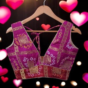 May include: A purple and gold brocade sleeveless blouse with a deep V-neckline and a tie closure at the back.