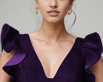 May include: A purple velvet blouse with a deep V-neckline and ruffled sleeves. The blouse is cropped and has a fitted silhouette. The text "Kanhasarees" is printed on the bottom of the blouse.