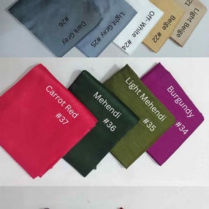 May include: A collection of fabric swatches in various colors, including pink, purple, green, gray, white, beige, red, and brown. Each swatch is labeled with a color name and a number.
