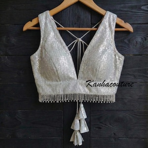 May include: A white ceramic mug with a black handle and the text "But First, Coffee" in a bold, black font. The mug is set against a blurred background, suggesting a cozy setting.