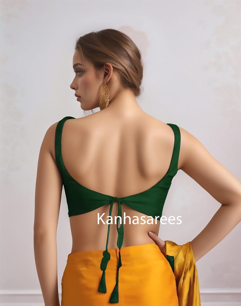 May include: A dark green sleeveless top with a low back and tie closure. The top is paired with a yellow skirt. The text "Kanhasarees" is visible on the garment.