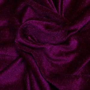 May include: Close-up of a deep purple velvet fabric with a soft, plush texture. The fabric is folded and draped, creating a luxurious and elegant look.