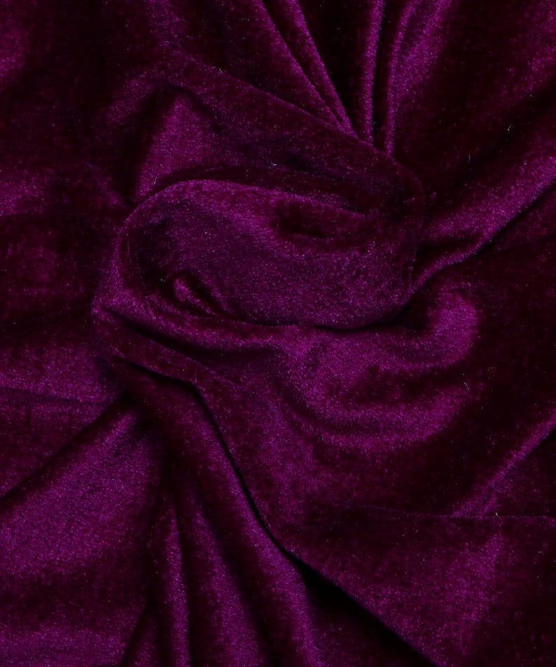 May include: Close-up of a deep purple velvet fabric with a soft, plush texture. The fabric is folded and draped, creating a luxurious and elegant look.