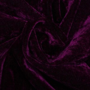 May include: Close-up of a deep purple velvet fabric with a soft, plush texture. The fabric is draped and folded, creating a luxurious and elegant look.