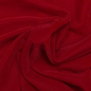 May include: Close-up of a deep red velvet fabric with soft, flowing folds. The fabric has a smooth, luxurious texture.