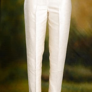 May include: Cream-colored, tailored pants with a straight leg and a subtle sheen. The pants have a classic design with a front crease and a tailored fit. The pants are paired with silver sandals.