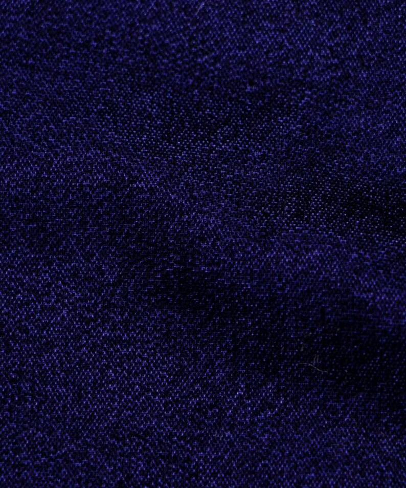 May include: A close-up of a dark blue fabric with a textured weave.