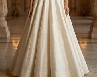 May include: A floor-length, off-white skirt featuring a high-waisted design with deep, structured pleats that create a voluminous, flared silhouette. The fabric has a subtle, textured sheen, extending from the waist to the floor.