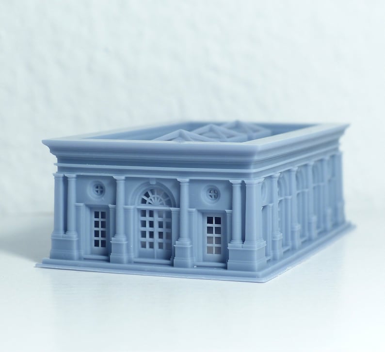 K&ouml;nnte beinhalten: Ein graues 3D-gedrucktes Modell eines Geb&auml;udes im klassischen Stil. Das Geb&auml;ude hat einen rechteckigen Sockel mit einem Satteldach und eine Reihe von S&auml;ulen entlang der Vorderfassade. An der Vorderseite des Geb&auml;udes befinden sich Fenster und T&uuml;ren.