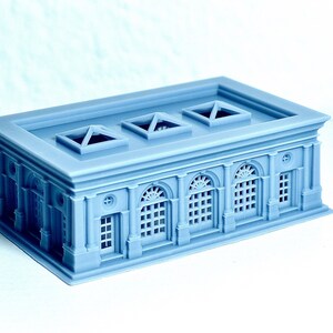 K&ouml;nnte beinhalten: Ein hellblaues Modell eines Geb&auml;udes mit einem Flachdach und drei Oberlichtern. Das Geb&auml;ude hat sechs Bogenfenster und einen dekorativen Rahmen um die Fenster und T&uuml;ren.