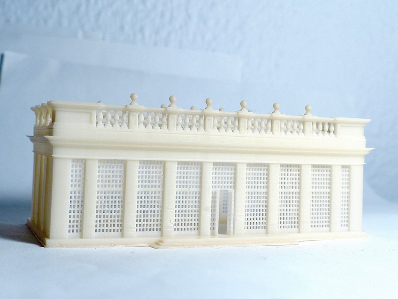May include: A white, detailed model of a classical building with a balcony and a latticework facade. The model is made of plastic and is approximately 6 inches long.