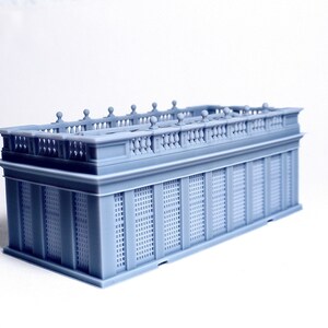 May include: A gray 3D printed model of a building with a detailed balcony and latticework facade.
