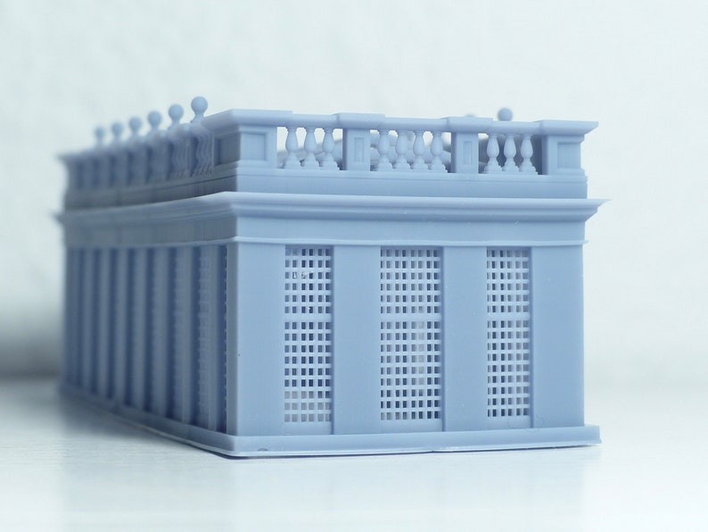 May include: A light gray 3D printed model of a building with a detailed facade and a balcony with a railing. The building has a series of windows with a grid pattern.