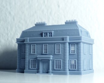 May include: A light blue 3D printed model of a two-story house with a brick facade and multiple windows.