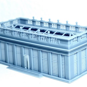 May include: A gray 3D printed model of a building with a detailed roof and a balcony. The building has a glass roof and a series of windows with a grid pattern.