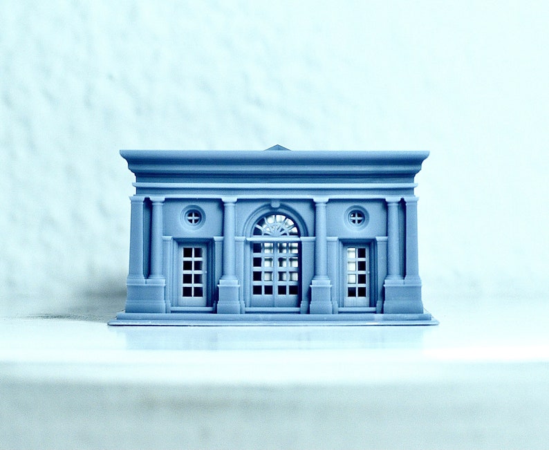 K&ouml;nnte beinhalten: Ein kleines, graues, 3D-gedrucktes Modell eines Geb&auml;udes im klassischen Stil. Das Geb&auml;ude hat einen zentralen Bogen mit zwei kleineren T&uuml;ren auf beiden Seiten. Das Geb&auml;ude hat ein Flachdach und ein dekoratives Gesims.