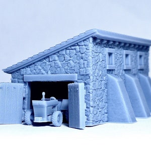 May include: A gray stone building with a garage door open, revealing a small gray tractor inside. The building has a sloped roof and three small windows on the side.