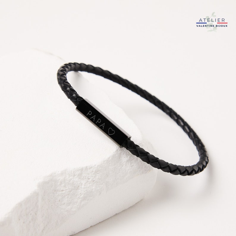 May include: Black leather bracelet with a silver bar engraved with "PAPA" and a heart symbol.