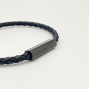 May include: Black leather bracelet with a black metal bar that says "PAPA" with a heart symbol.